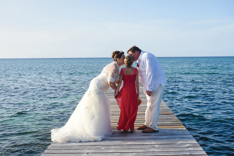 Wedding couple kissing girl